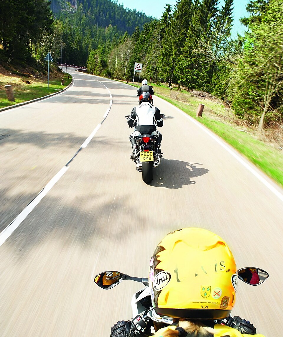 Three motorbikes being ridden along a mountain road