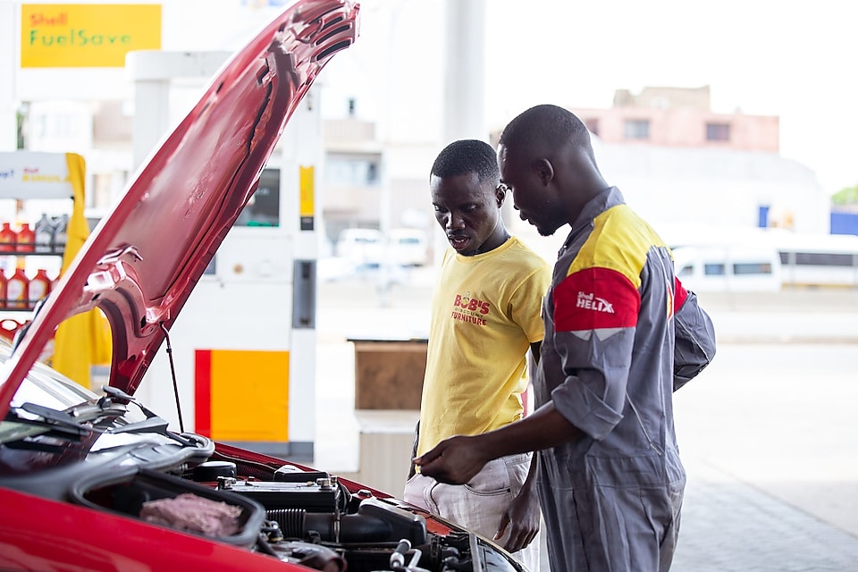 Shell assistant opening bonet of a car to check the oil