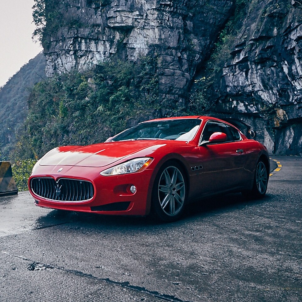 A red Maserati with standard Shell Helix Ultra product proudly sits on a scenic mountain road