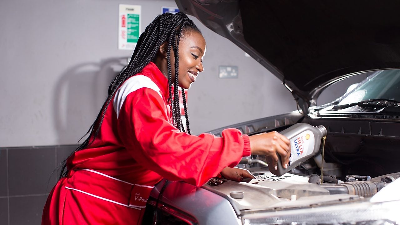 engineer pouring Shell lubricant into a car engine