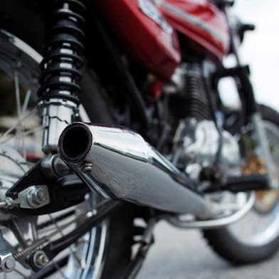 motorcycle parked on road with camera focused on the exhaust and wheels