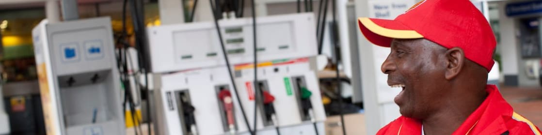Forecourt attendant standing next to a pump