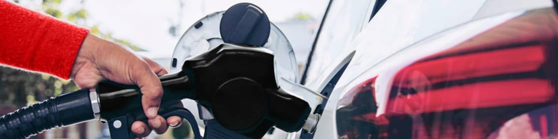 Person refueling car with fuel nozzle at gas station
