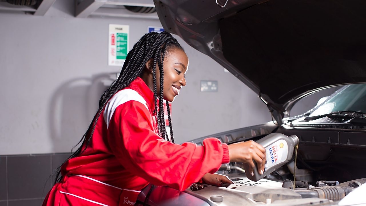 engineer pouring Shell lubricant into a car engine