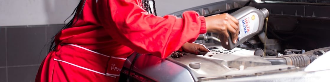 engineer pouring Shell lubricant into a car engine