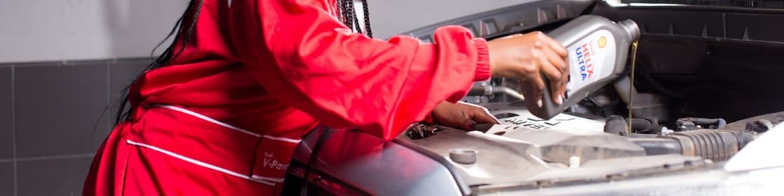 engineer pouring Shell lubricant into a car engine